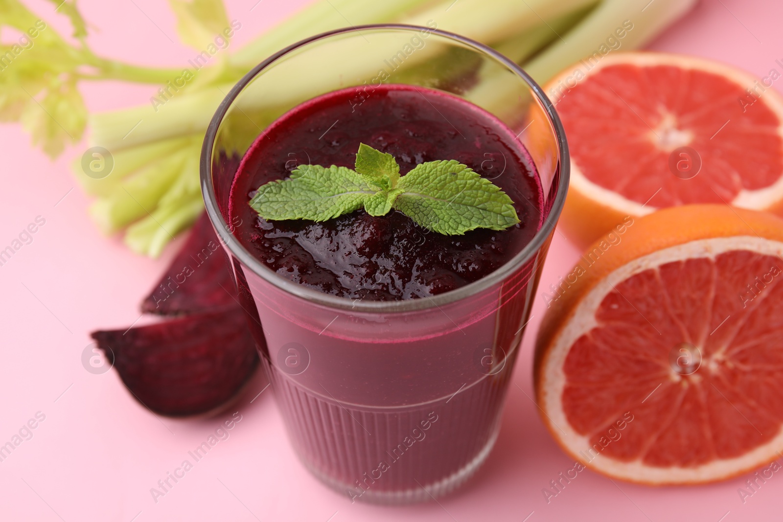 Photo of Fresh beetroot smoothie and mint in glass on pink table, closeup