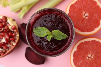 Photo of Fresh beetroot smoothie and mint in glass on pink table, flat lay. Vegan drink