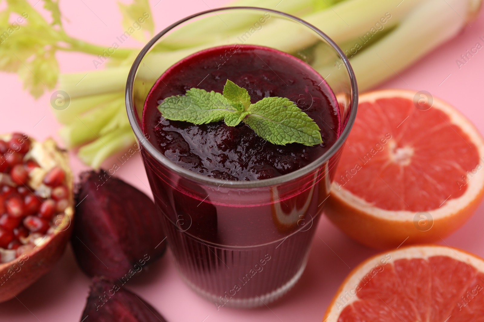 Photo of Fresh beetroot smoothie and mint in glass on pink table, closeup