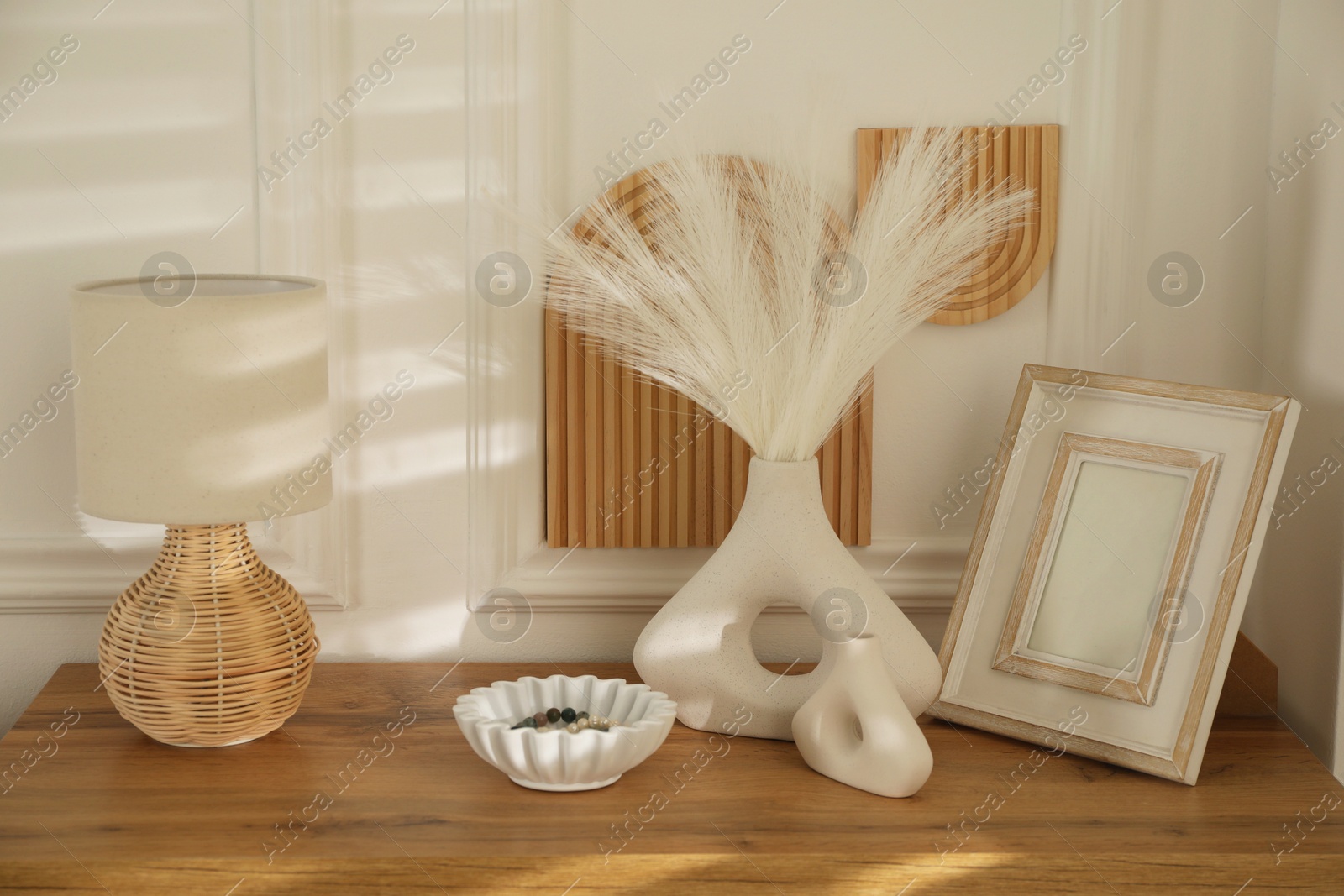 Photo of Beautiful decorative plants, vases, photo frame, ceramic bowl and lamp on wooden table indoors