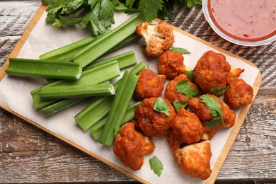 Photo of Baked cauliflower buffalo wings with parsley served on wooden table, flat lay