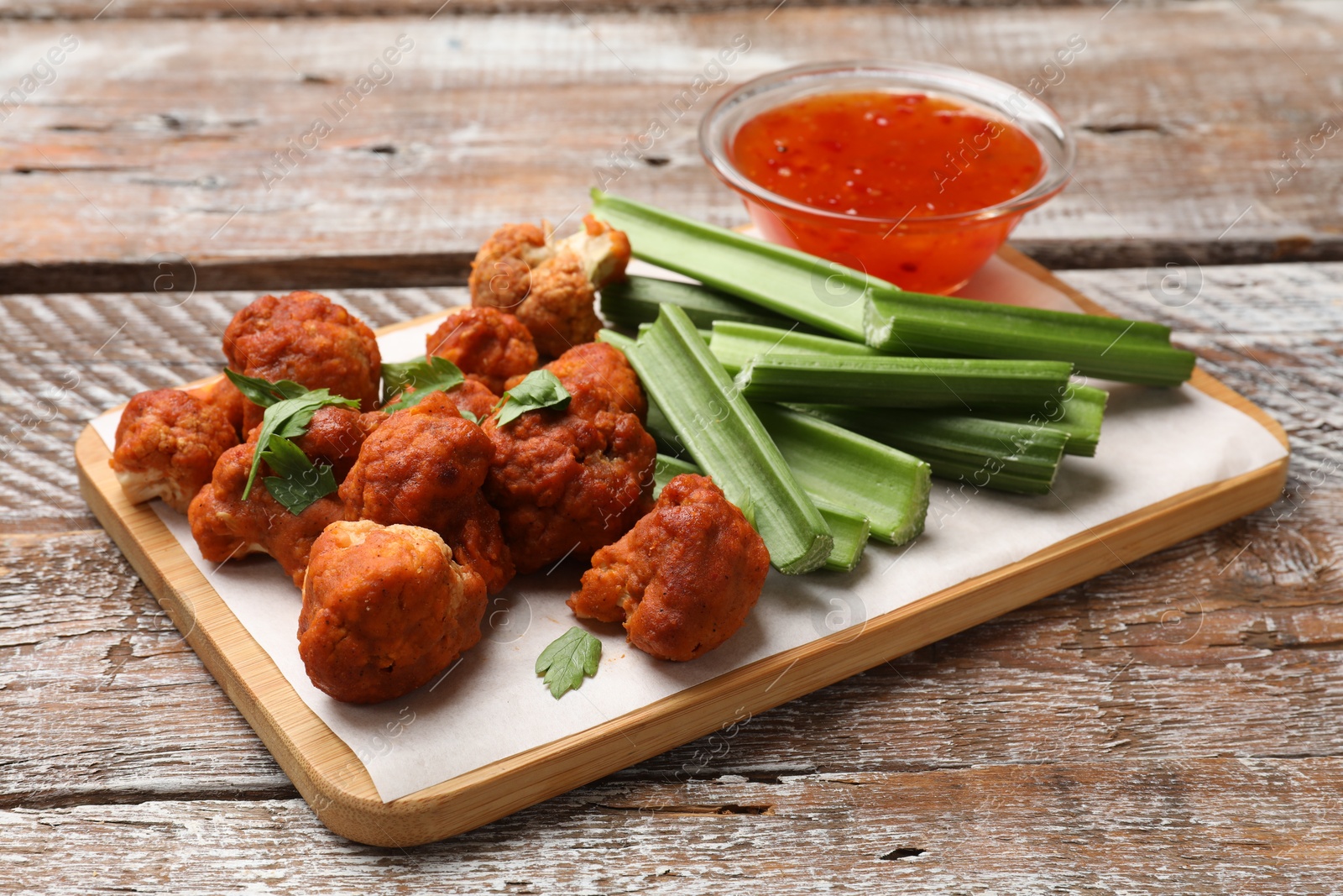 Photo of Baked cauliflower buffalo wings with parsley served on wooden table