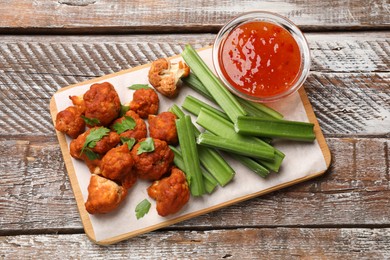 Photo of Baked cauliflower buffalo wings with parsley served on wooden table, top view