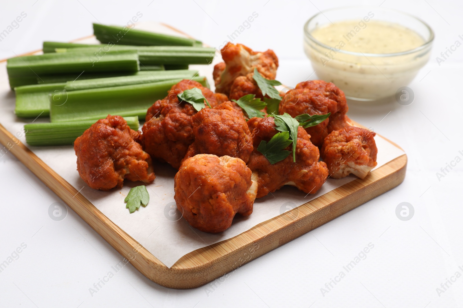 Photo of Baked cauliflower buffalo wings with parsley served on white table, closeup