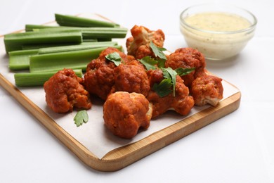 Photo of Baked cauliflower buffalo wings with parsley served on white table, closeup