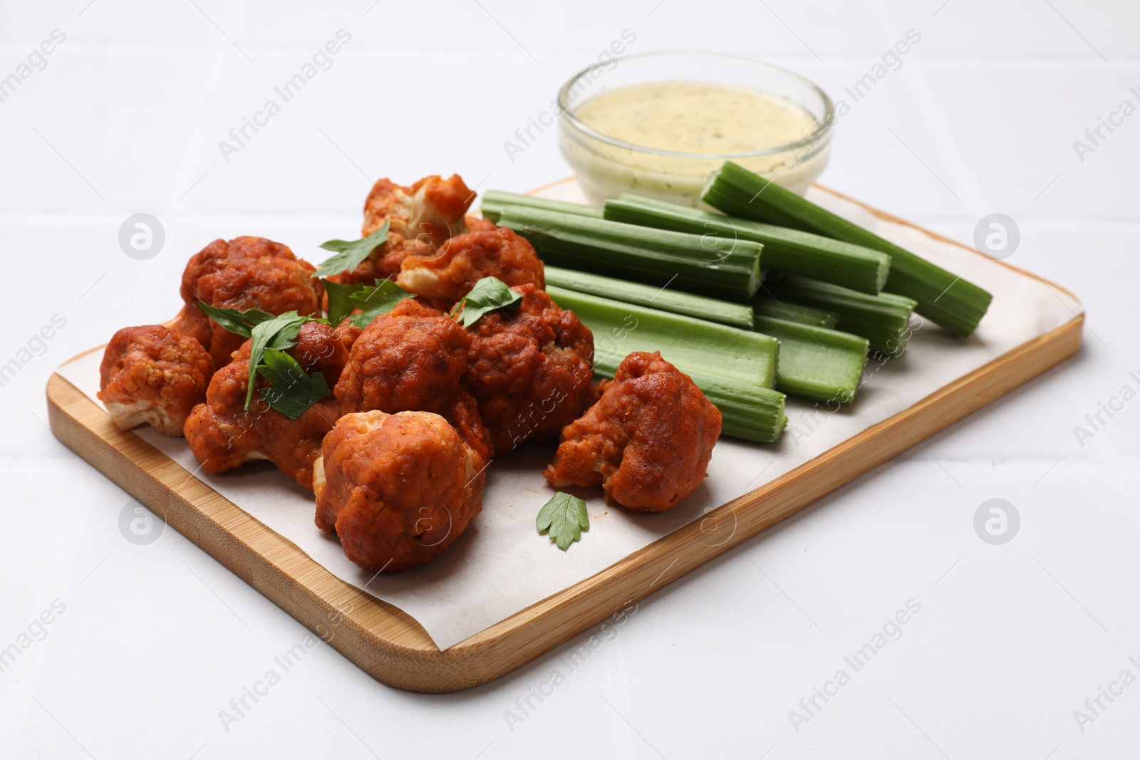 Photo of Baked cauliflower buffalo wings with parsley served on white table