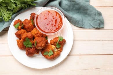 Photo of Baked cauliflower buffalo wings with parsley and sauce on wooden table, flat lay