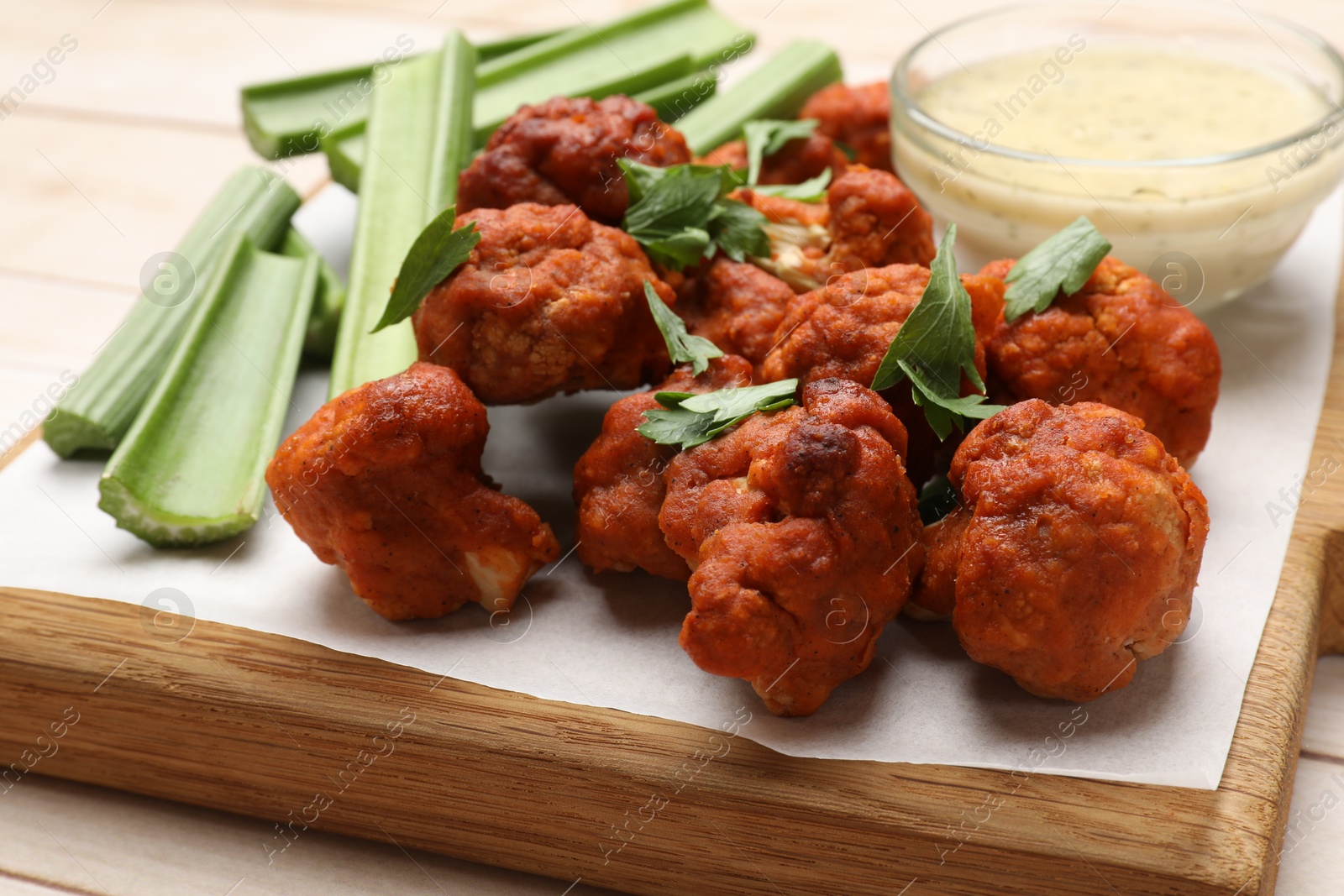 Photo of Baked cauliflower buffalo wings served on wooden table, closeup