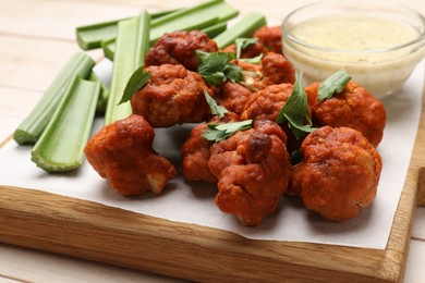 Photo of Baked cauliflower buffalo wings served on wooden table, closeup