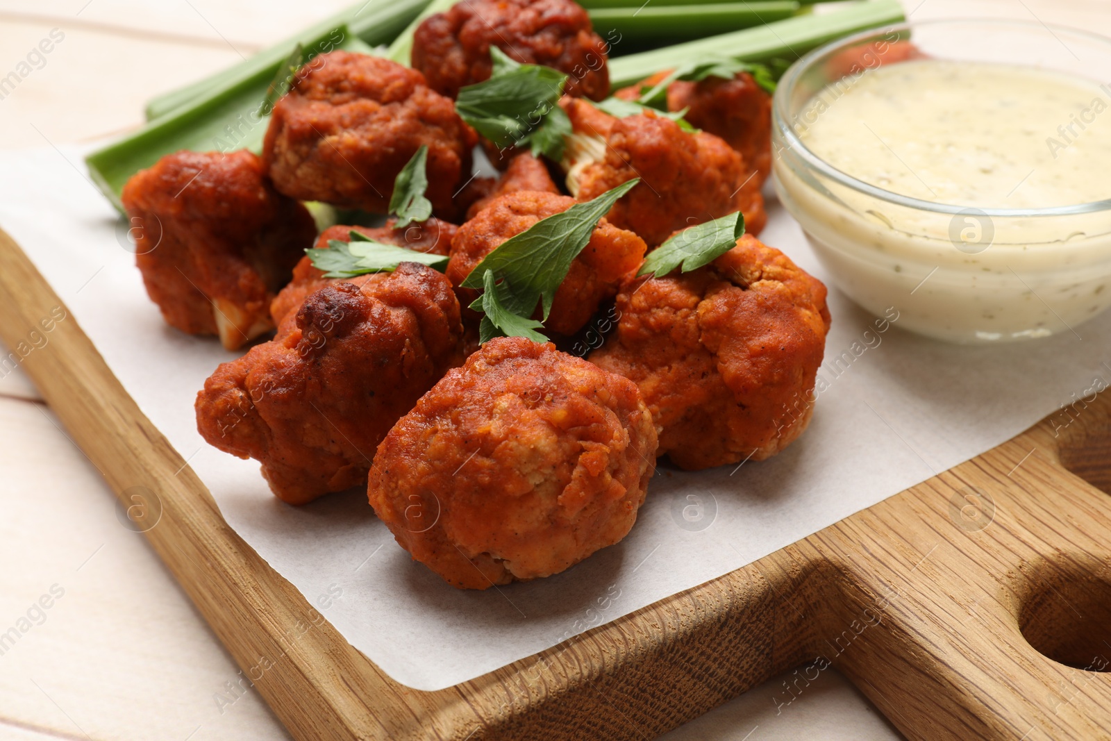 Photo of Baked cauliflower buffalo wings served on wooden table, closeup