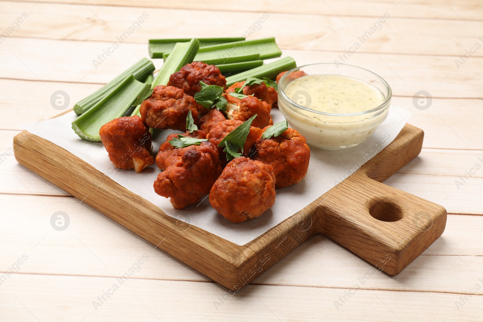 Photo of Baked cauliflower buffalo wings served on wooden table