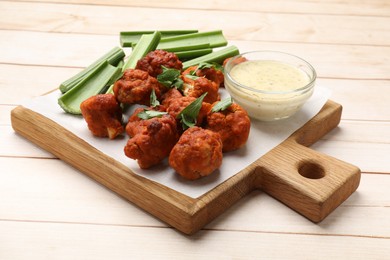 Photo of Baked cauliflower buffalo wings served on wooden table