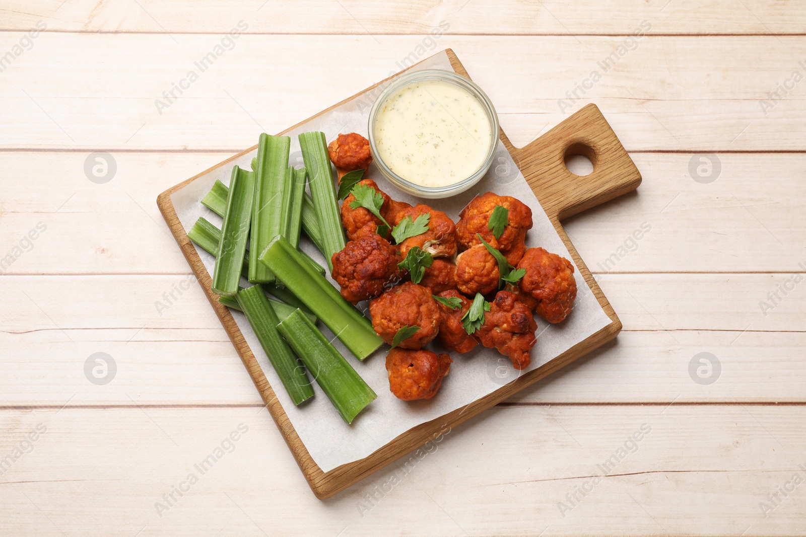 Photo of Baked cauliflower buffalo wings served on wooden table, top view