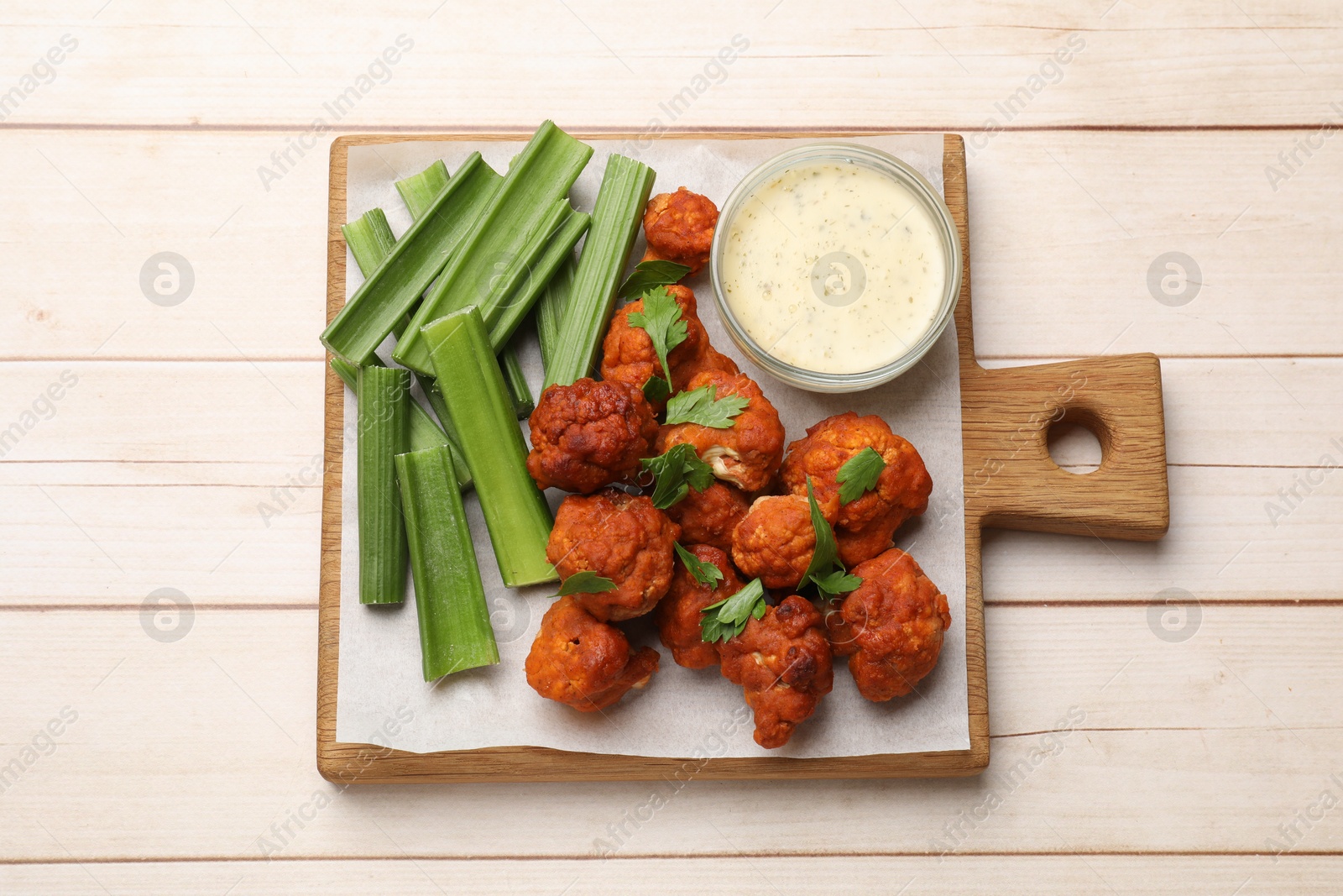 Photo of Baked cauliflower buffalo wings served on wooden table, top view