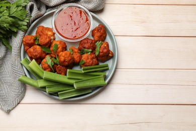 Photo of Baked cauliflower buffalo wings served on wooden table, top view. Space for text