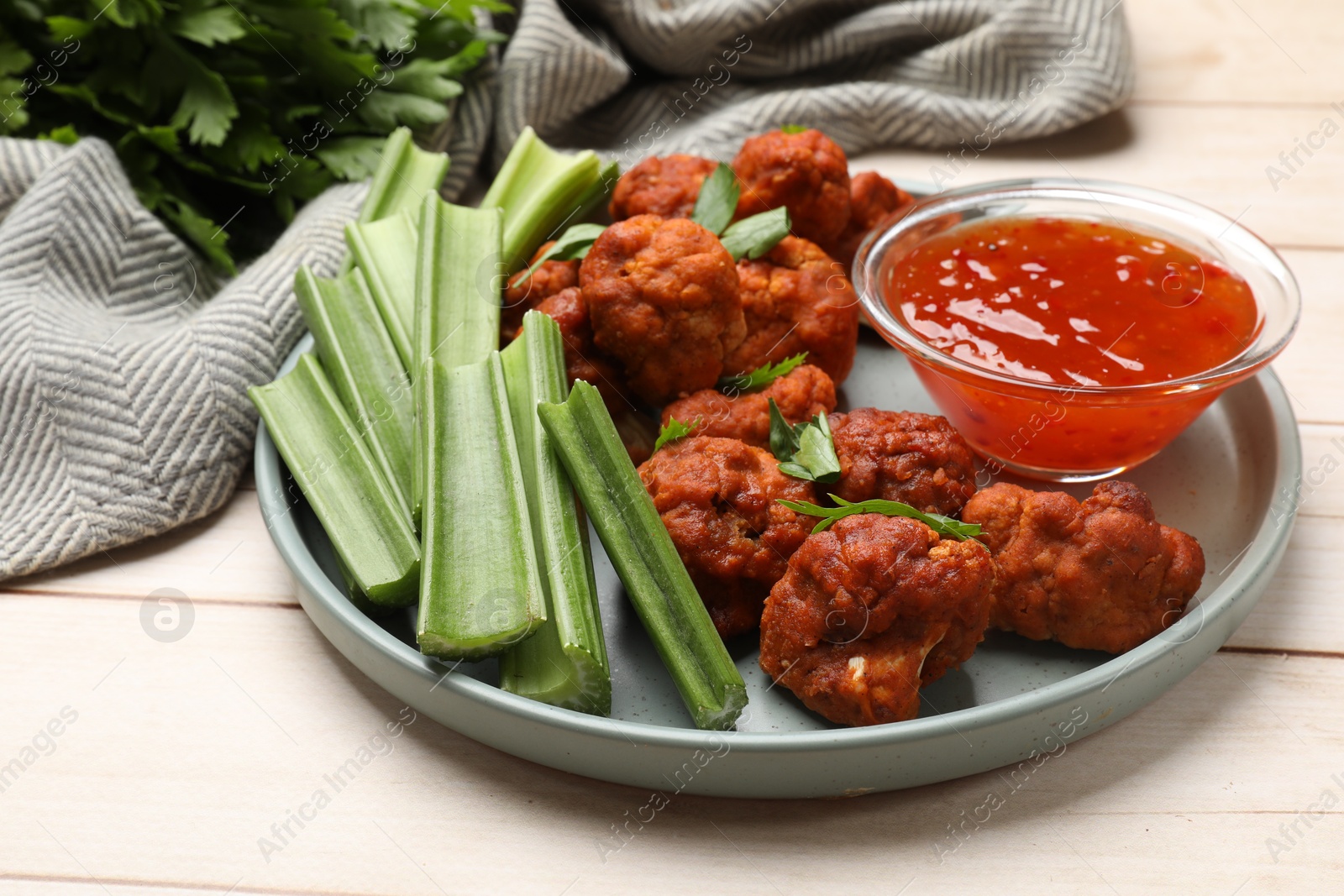 Photo of Baked cauliflower buffalo wings served on wooden table, closeup