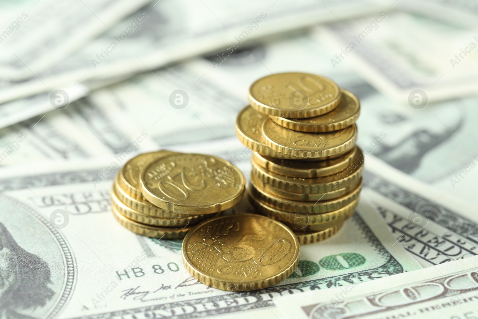 Photo of Many euro coins on dollar banknotes, closeup