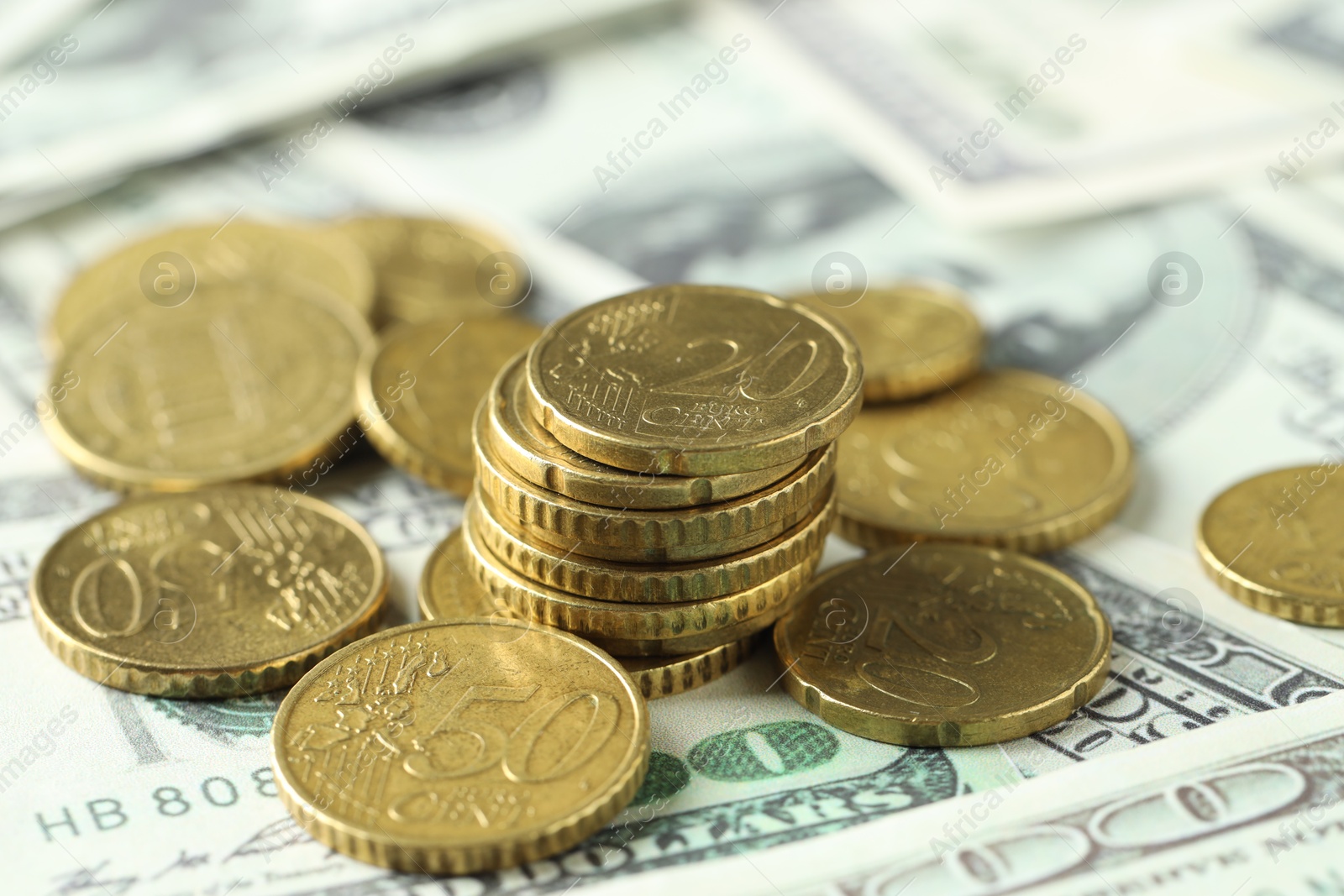 Photo of Many euro coins on dollar banknotes, closeup