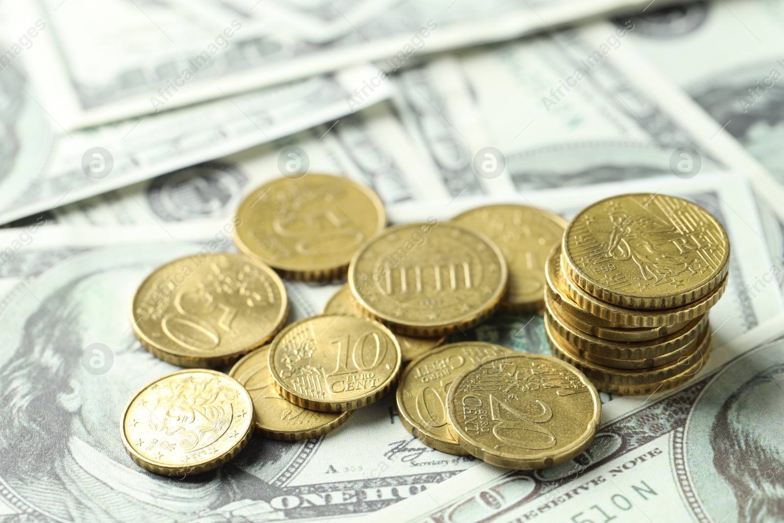 Photo of Many euro coins on dollar banknotes, closeup