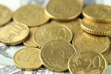 Photo of Many euro coins on dollar banknotes, closeup