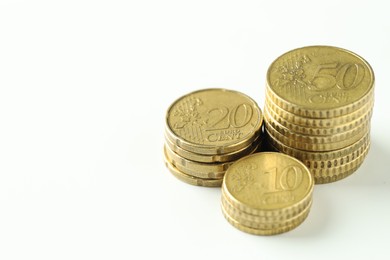 Photo of Stacked euro coins on white background, closeup. Space for text