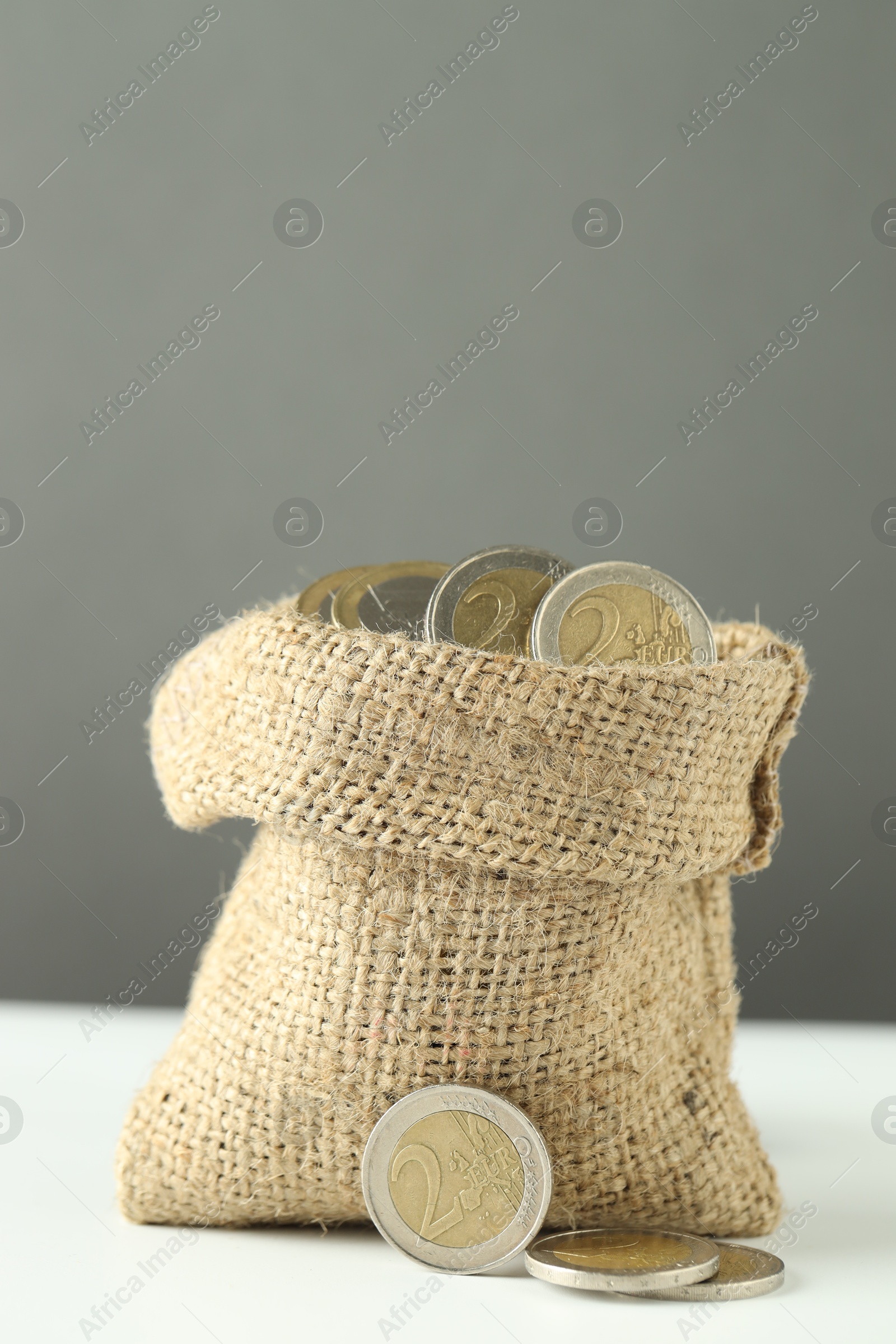 Photo of Euro coins in burlap sack on white table