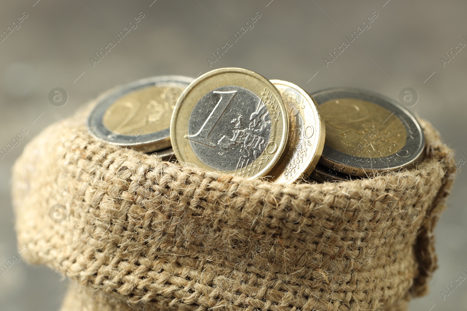 Photo of Euro coins in burlap sack on blurred background, closeup