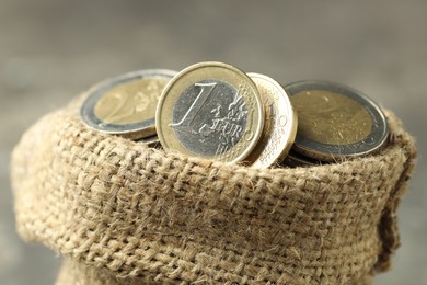 Photo of Euro coins in burlap sack on blurred background, closeup