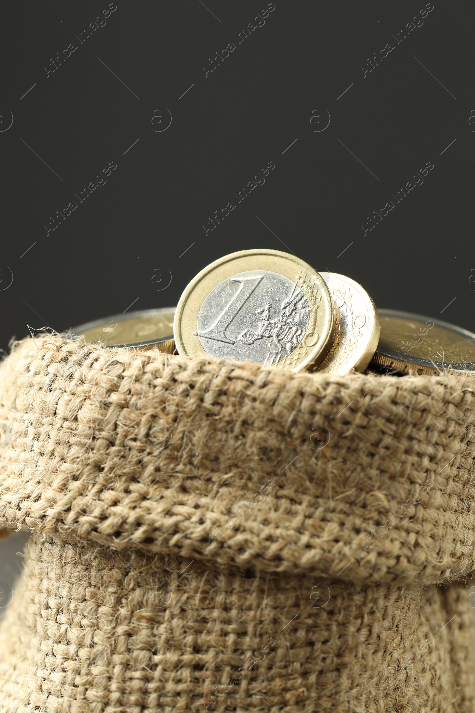 Photo of Euro coins in burlap sack on grey background, closeup