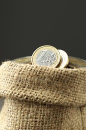 Euro coins in burlap sack on grey background, closeup