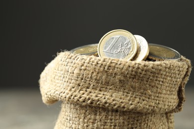 Photo of Euro coins in burlap sack on grey background, closeup