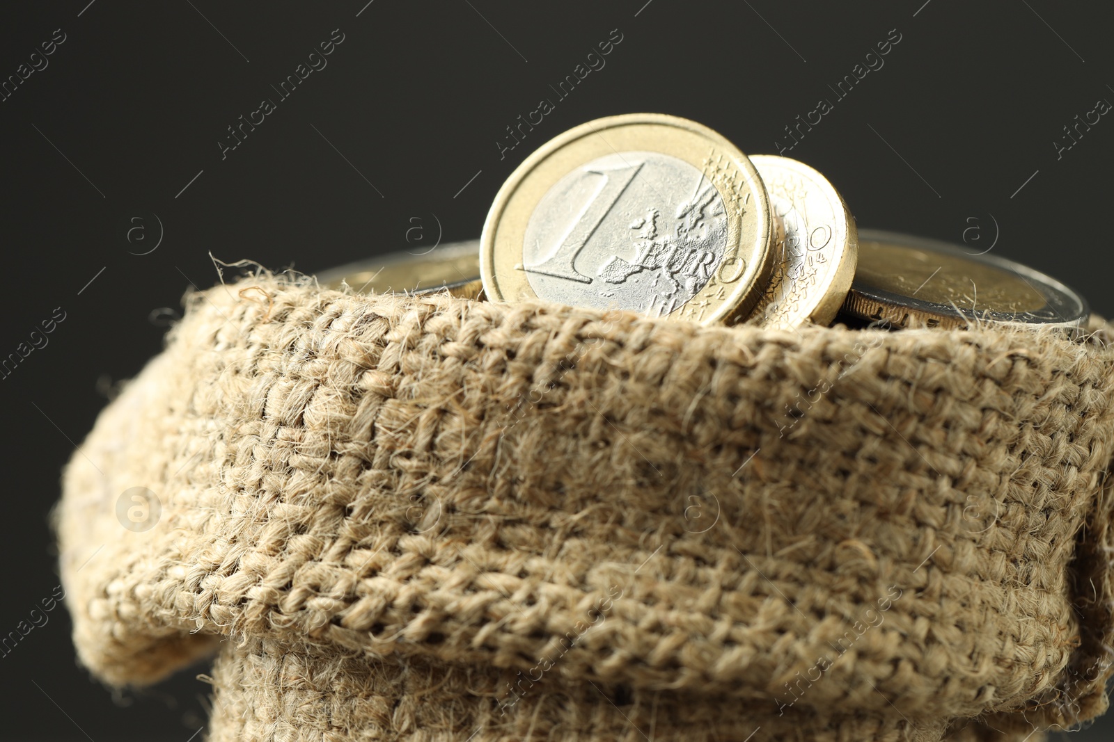 Photo of Euro coins in burlap sack on grey background, closeup