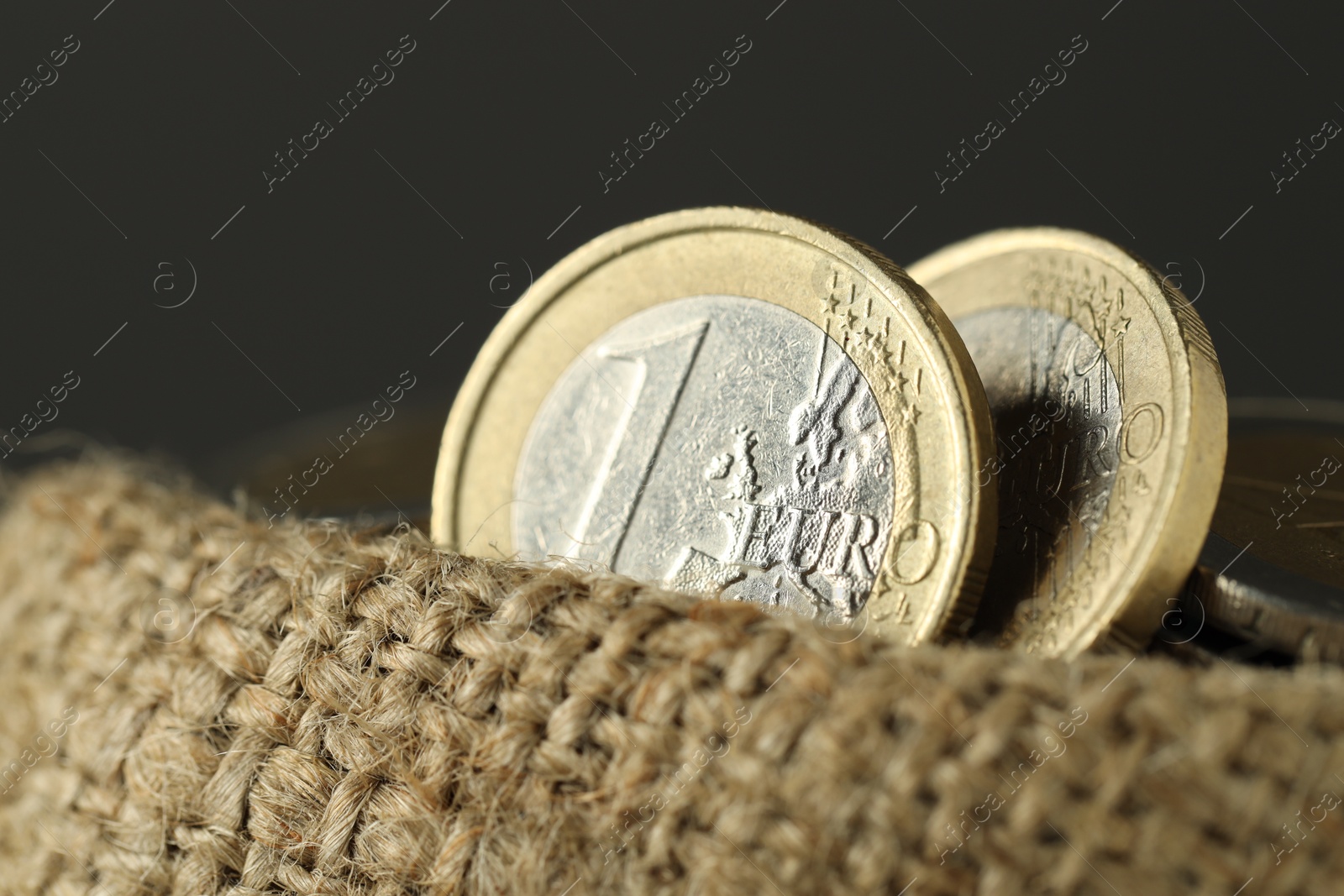 Photo of Euro coins in burlap sack on grey background, closeup