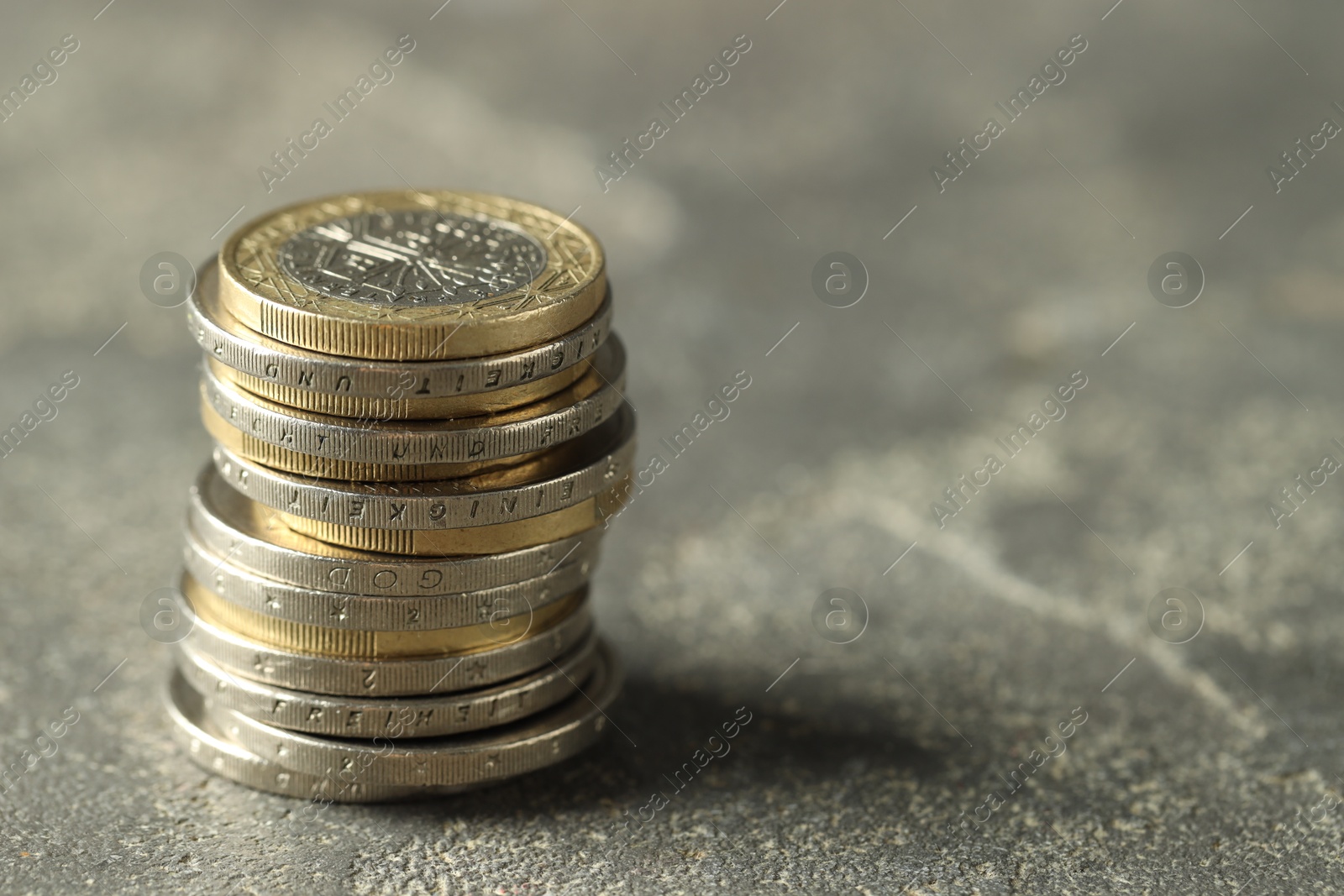 Photo of Stacked euro coins on grey table, space for text