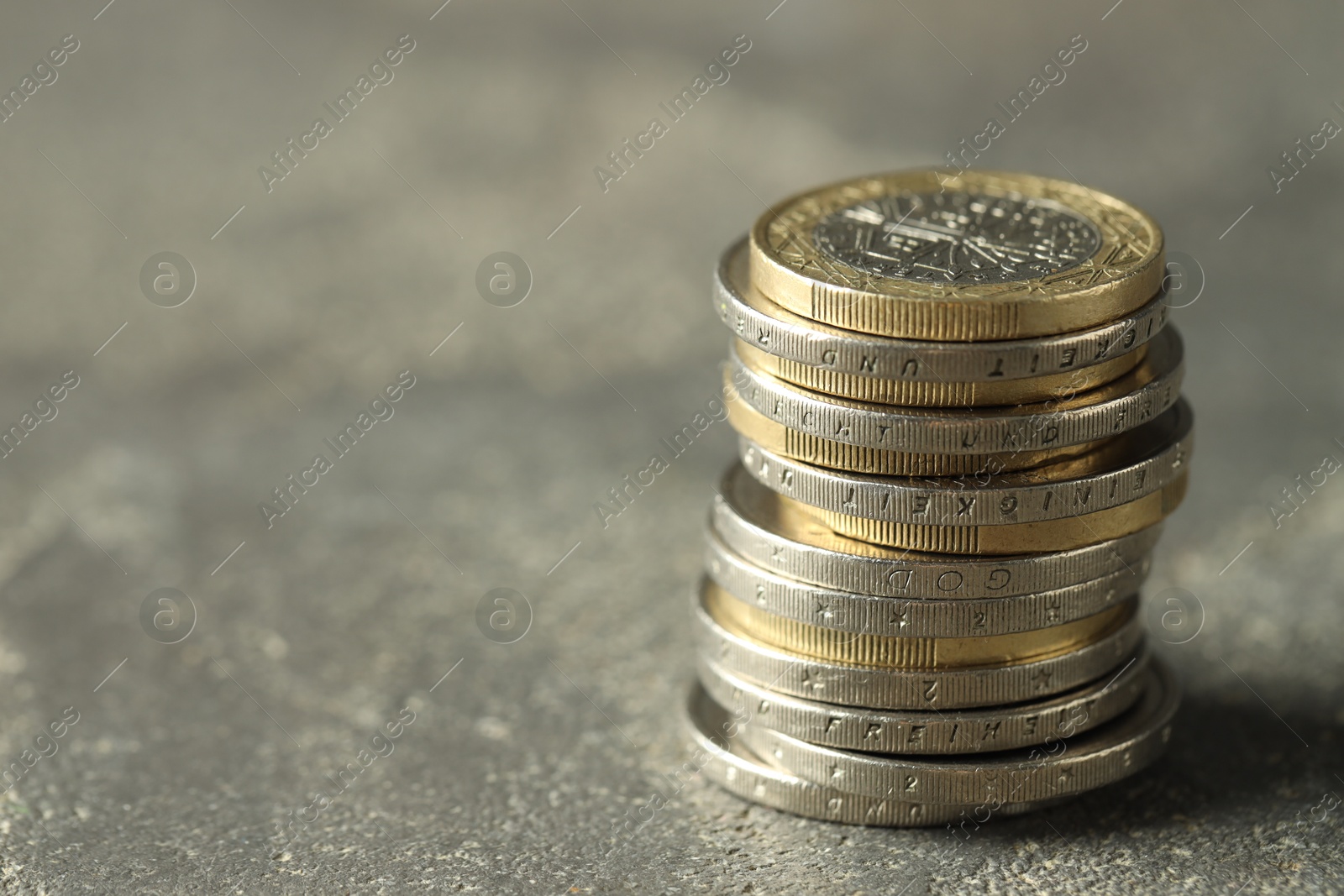 Photo of Stacked euro coins on grey table, space for text