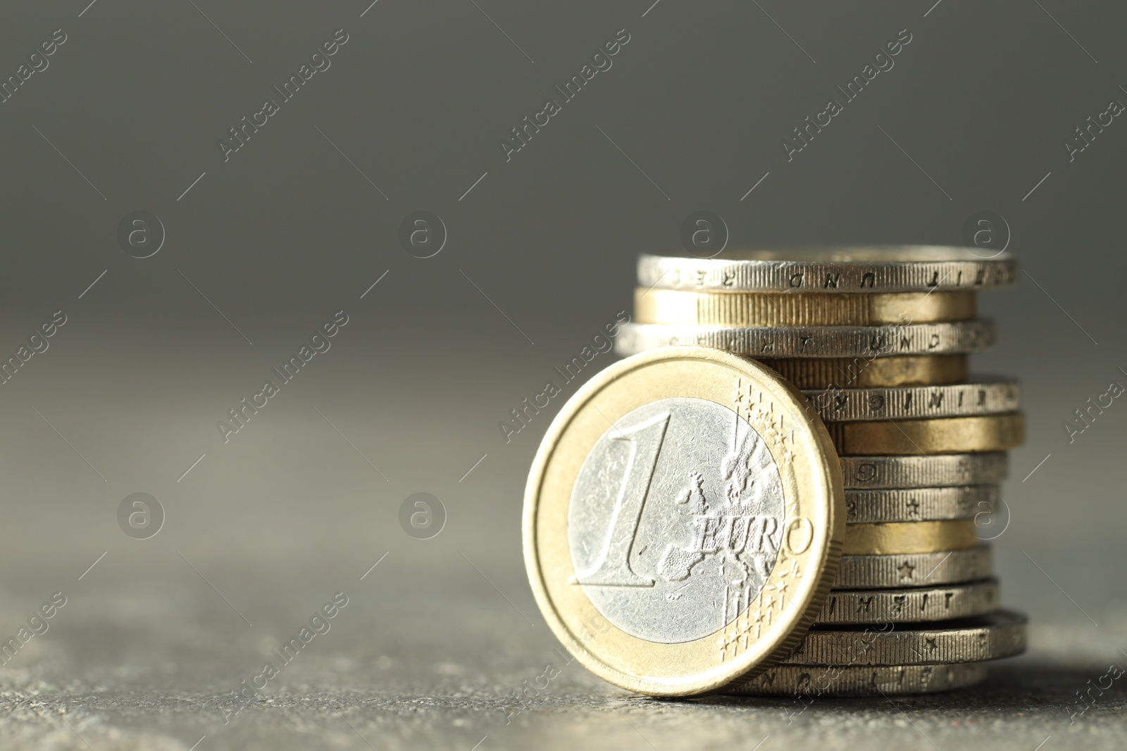 Photo of Euro coins on grey table, space for text