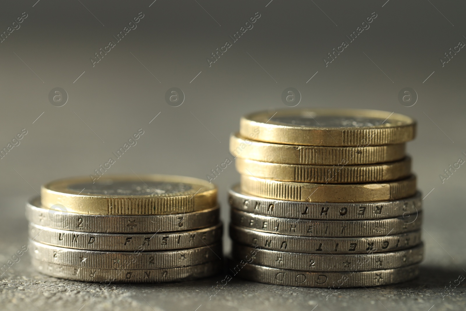 Photo of Stacked euro coins on grey table, closeup