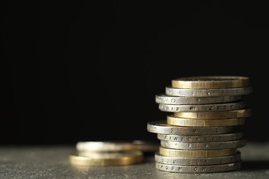 Photo of Stacked euro coins on grey table, closeup. Space for text