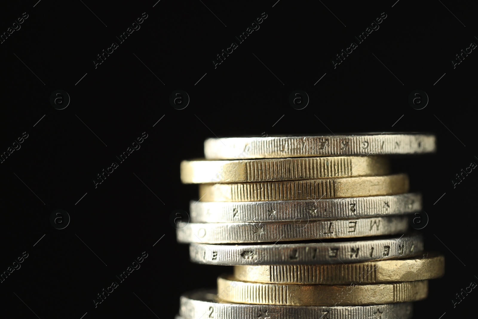 Photo of Stacked euro coins on black background, closeup. Space for text