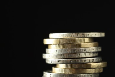 Photo of Stacked euro coins on black background, closeup. Space for text