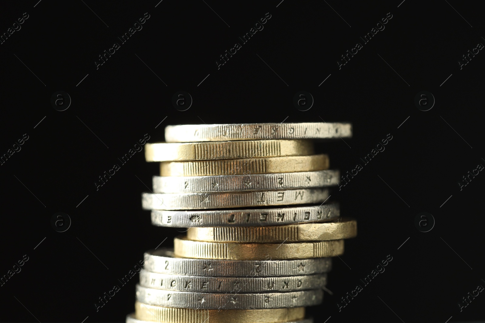 Photo of Stacked euro coins on black background, closeup