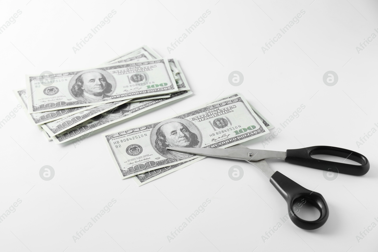 Photo of Budgeting. Dollar banknotes and scissors on white background