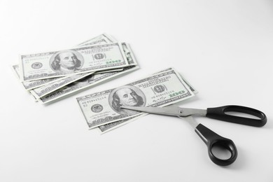 Budgeting. Dollar banknotes and scissors on white background