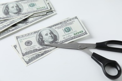 Photo of Budgeting. Dollar banknotes and scissors on white background, closeup