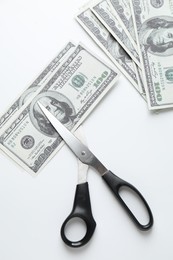 Photo of Budgeting. Dollar banknotes and scissors on white background, top view