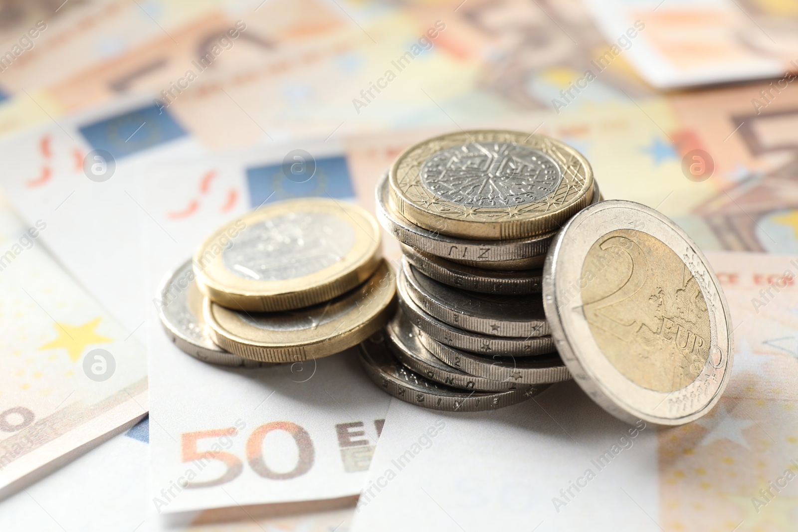 Photo of Many coins on euro banknotes, closeup view