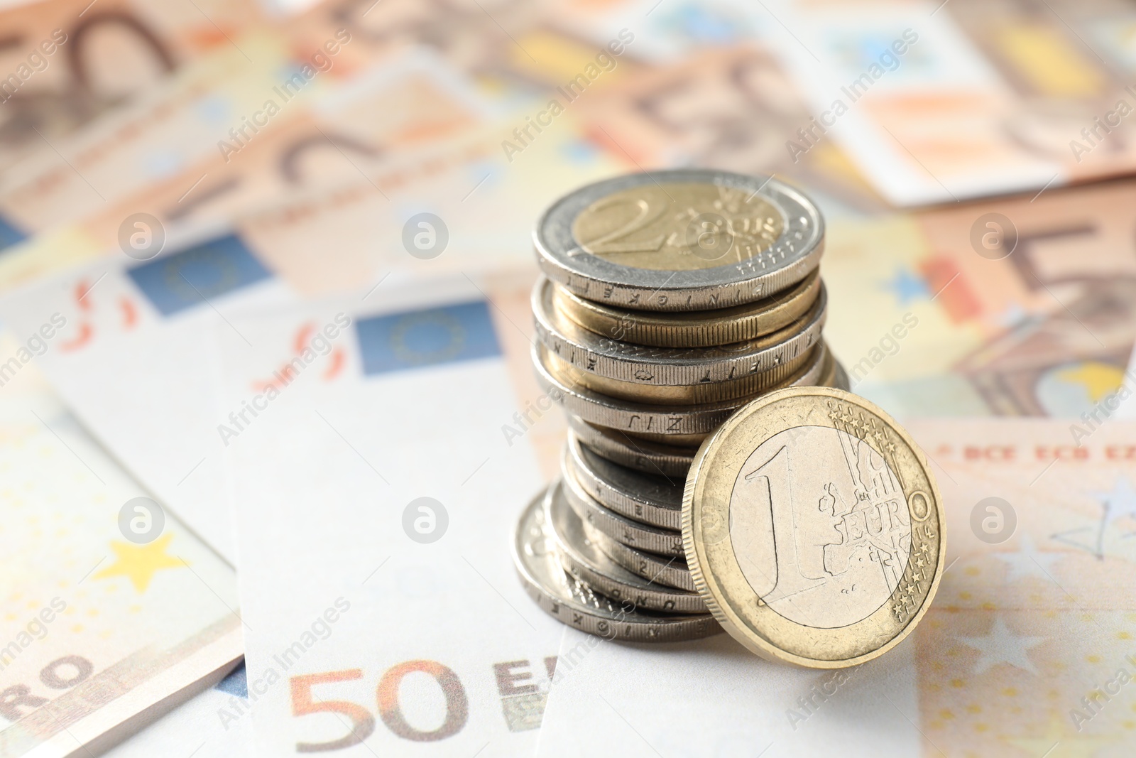 Photo of Stack of coins on euro banknotes, closeup. Space for text