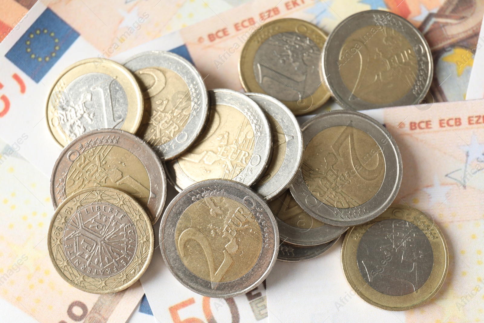 Photo of Many coins on euro banknotes, top view