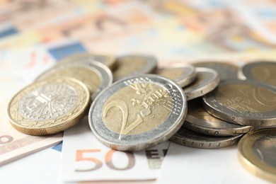 Photo of Many coins on euro banknotes, closeup view