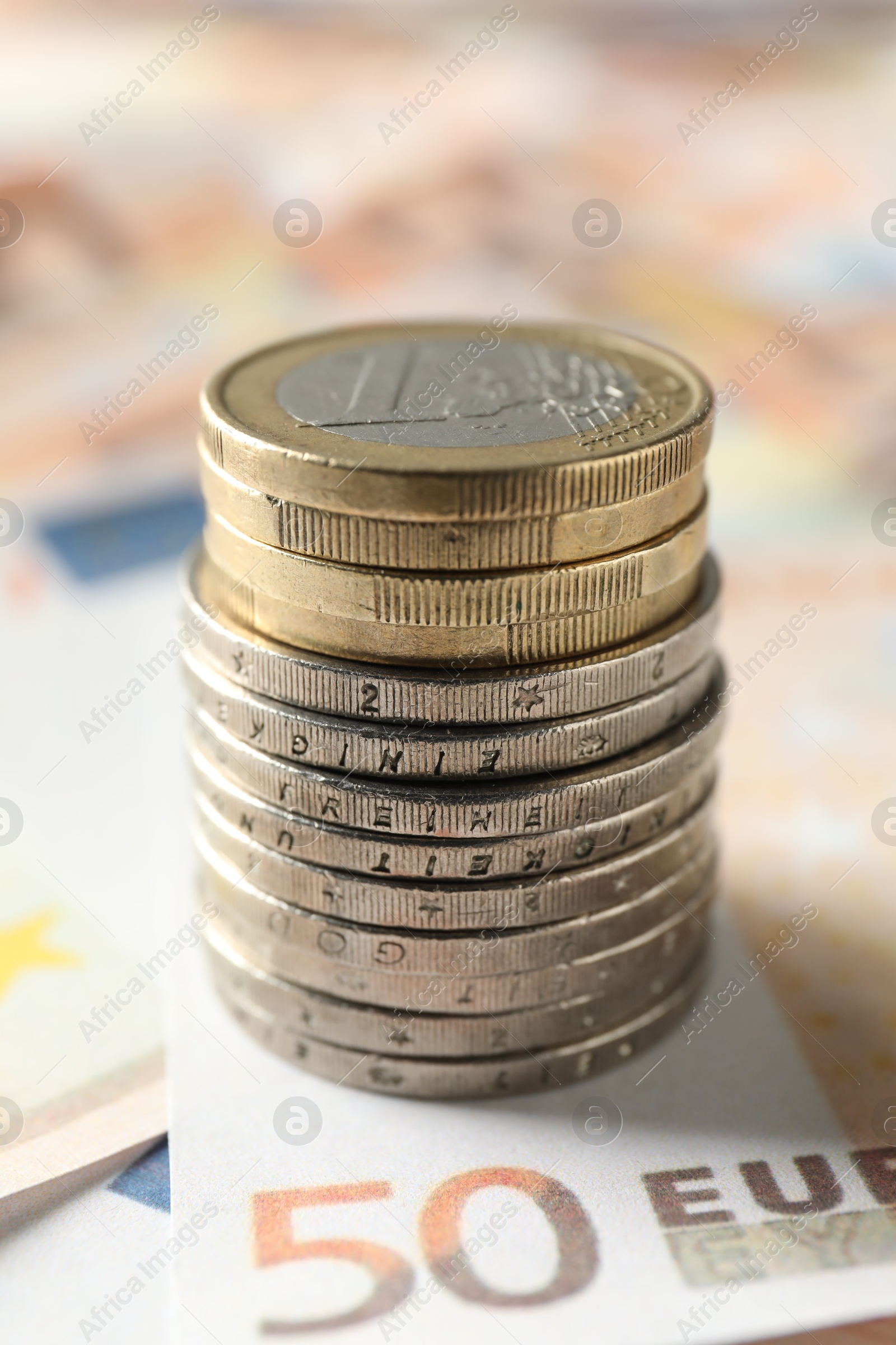 Photo of Stack of coins on euro banknotes, closeup